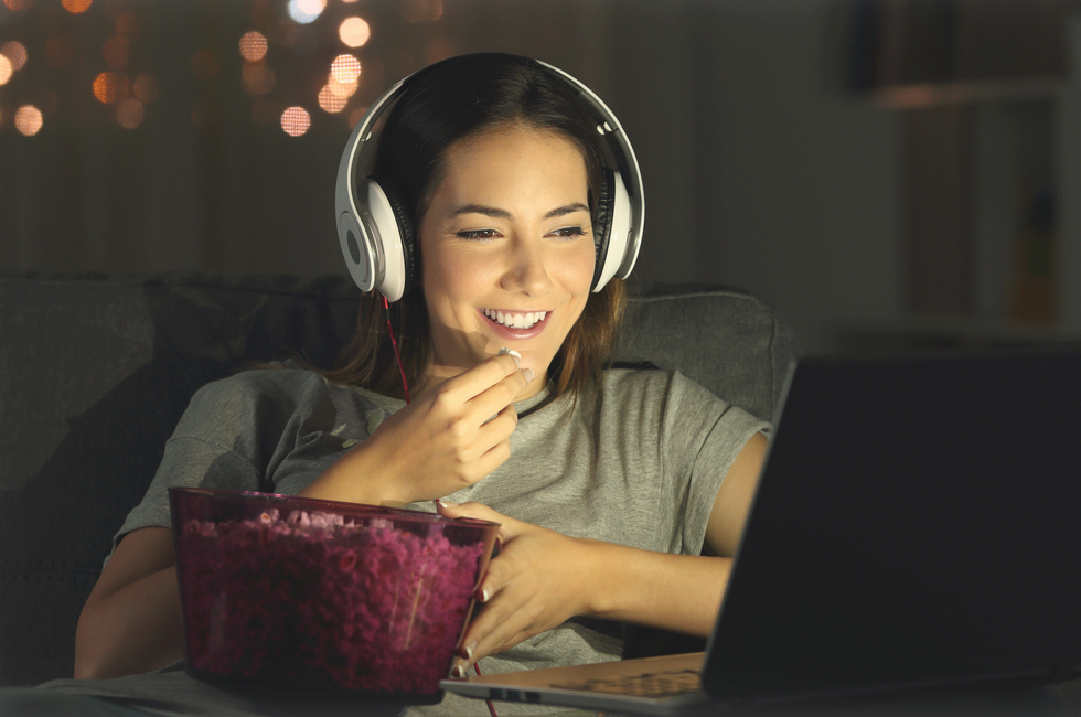 Kvinne ser film på pc og spiser popcorn - Klikk for stort bilde