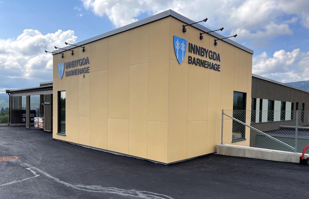 Deler av et bygg har gule fasadeplater med skilt på to av ytterveggene - Klikk for stort bilde