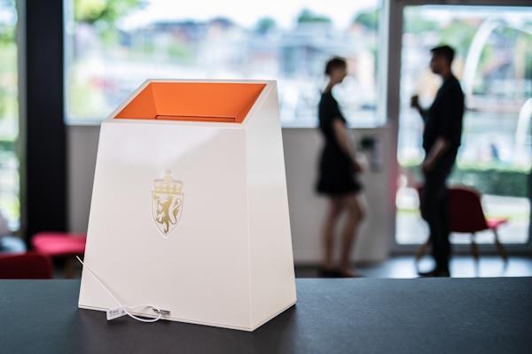 Bak en valgurne skimtes en mann og en kvinne som snakker sammen