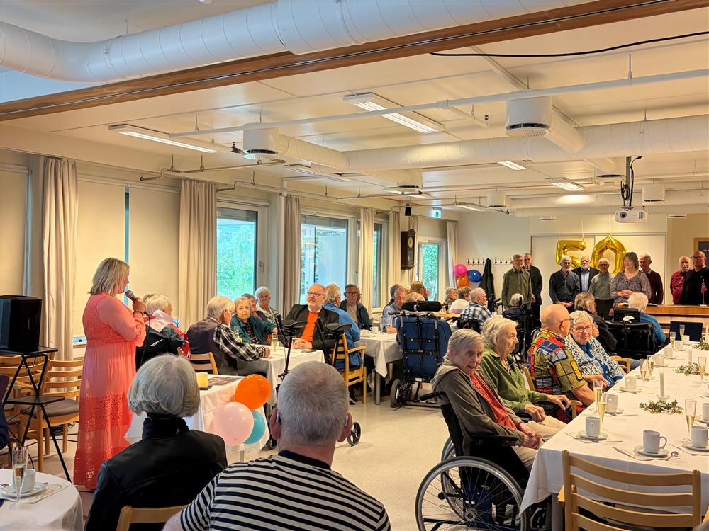 dame taler foran publikum i arbeidsstua på sykehjemmet - Klikk for stort bilde
