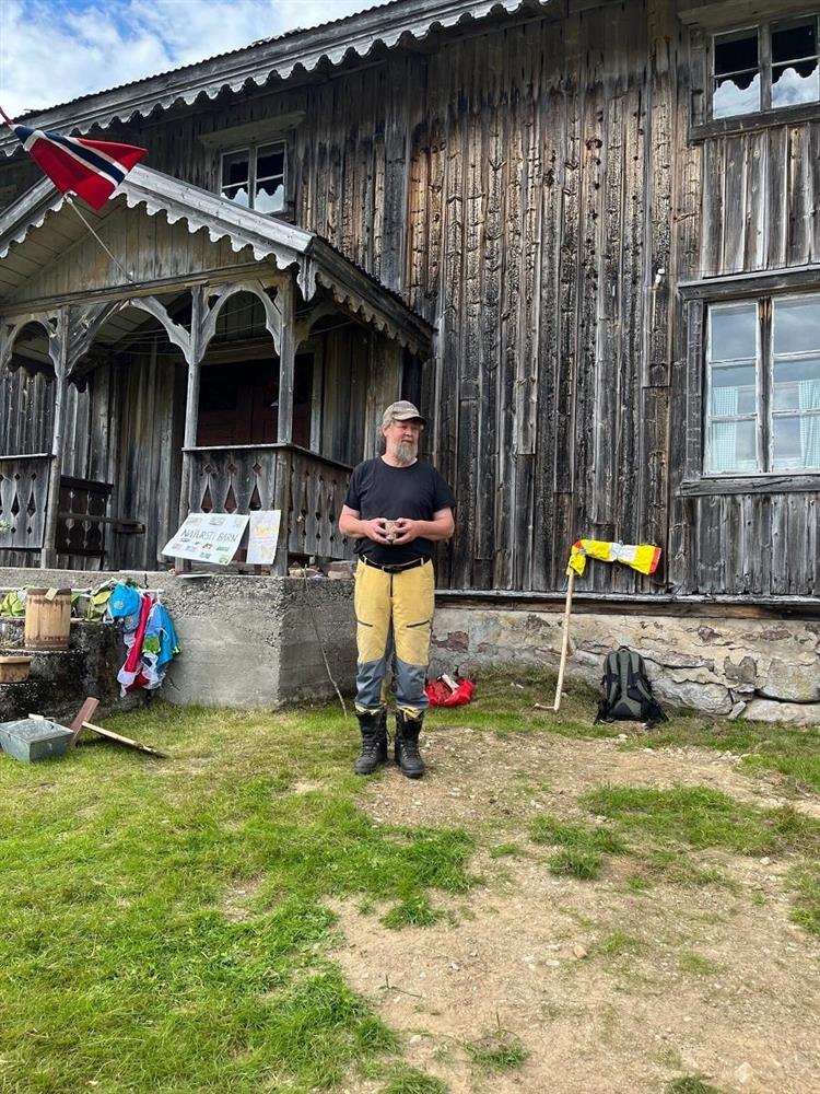 Bilde av en mann som står foran et gammelt hus med en kaffekopp i hendene - Klikk for stort bilde