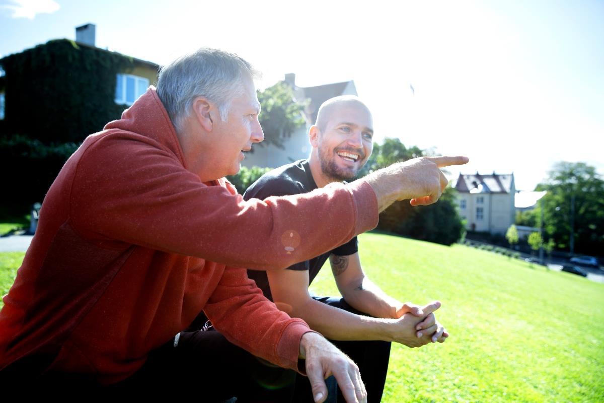 Eldre og ung mann i samtale på plen - Klikk for stort bilde